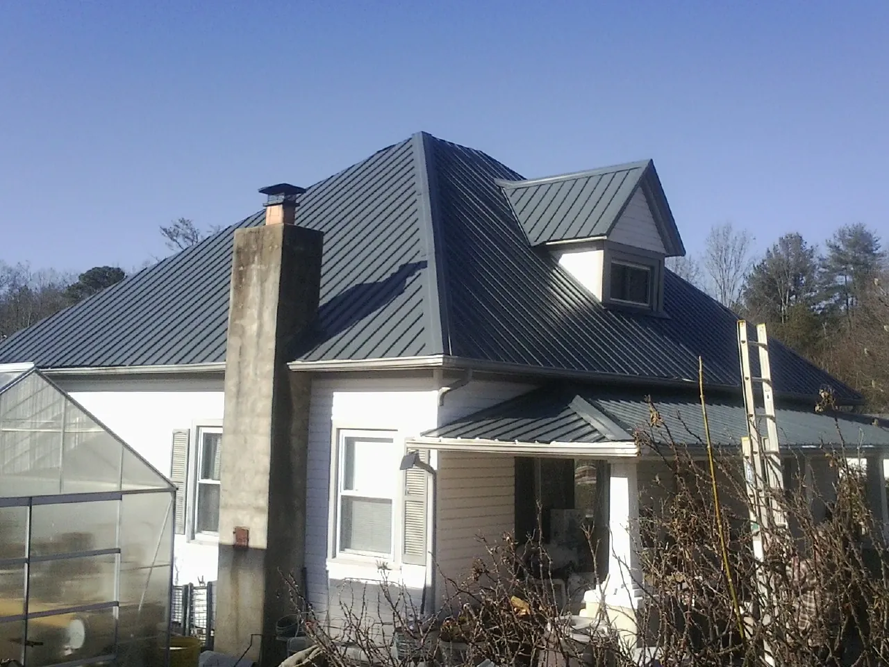 Dark blue standing seam metal roof on a white farmhouse with dormer — Slate & Tile Roof Repair by Roofing Brothers in Dalzell