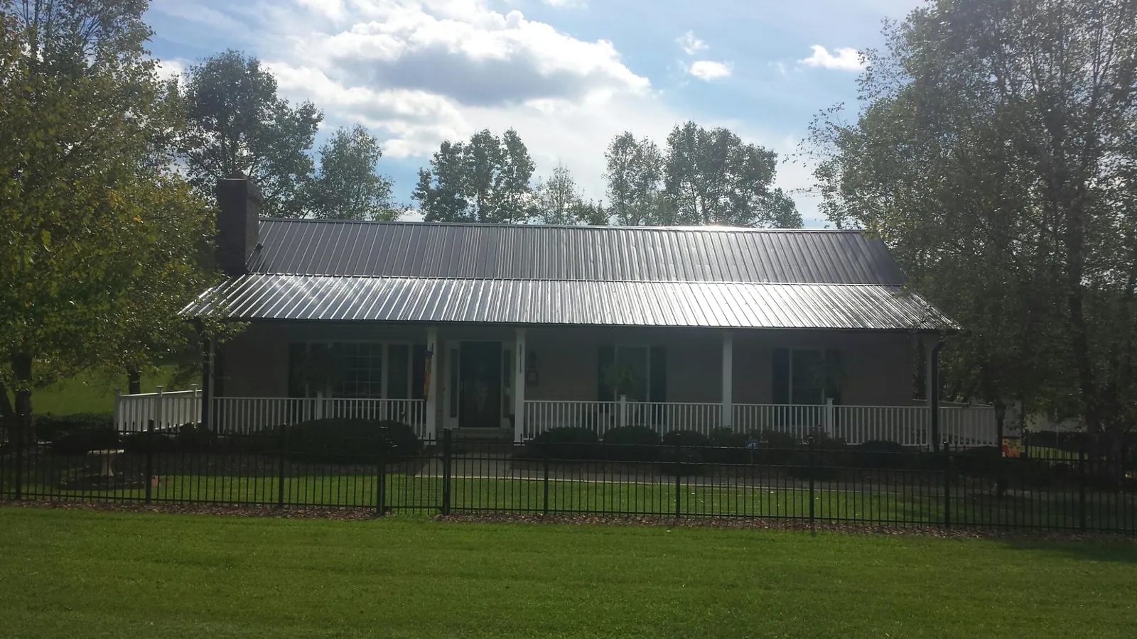 Gray metal roof on a brick ranch with a full width front porch — Gutter Guard Installation work by our crew in Dalzell