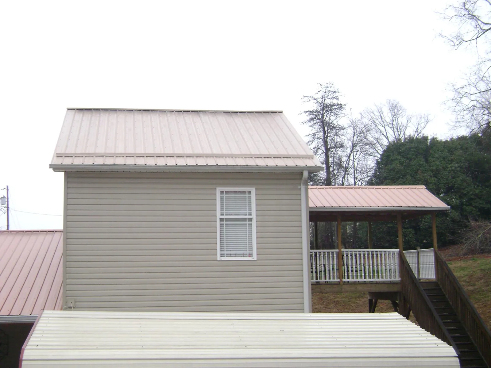 Tan metal roofs on a two story addition and attached porch, from a Roof Replacement job in Dalzell