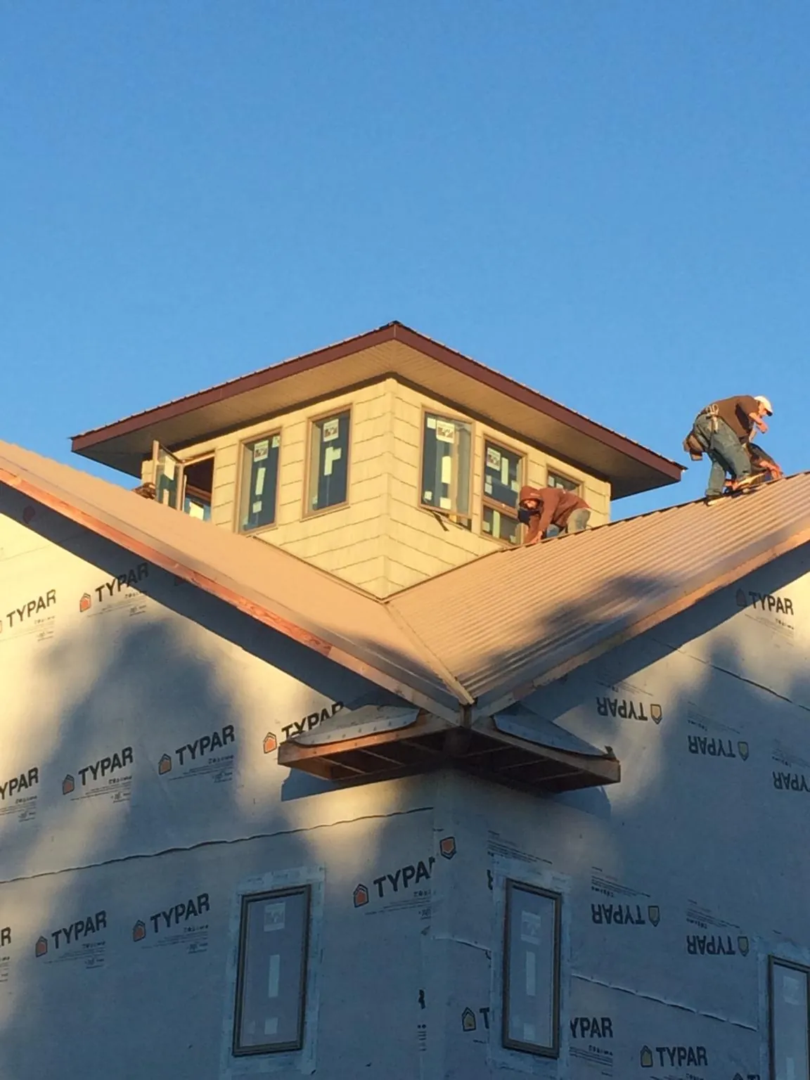 Roofers working around a rooftop cupola on a new metal roof at sunset — Roof Waterproofing in Dalzell by Roofing Brothers